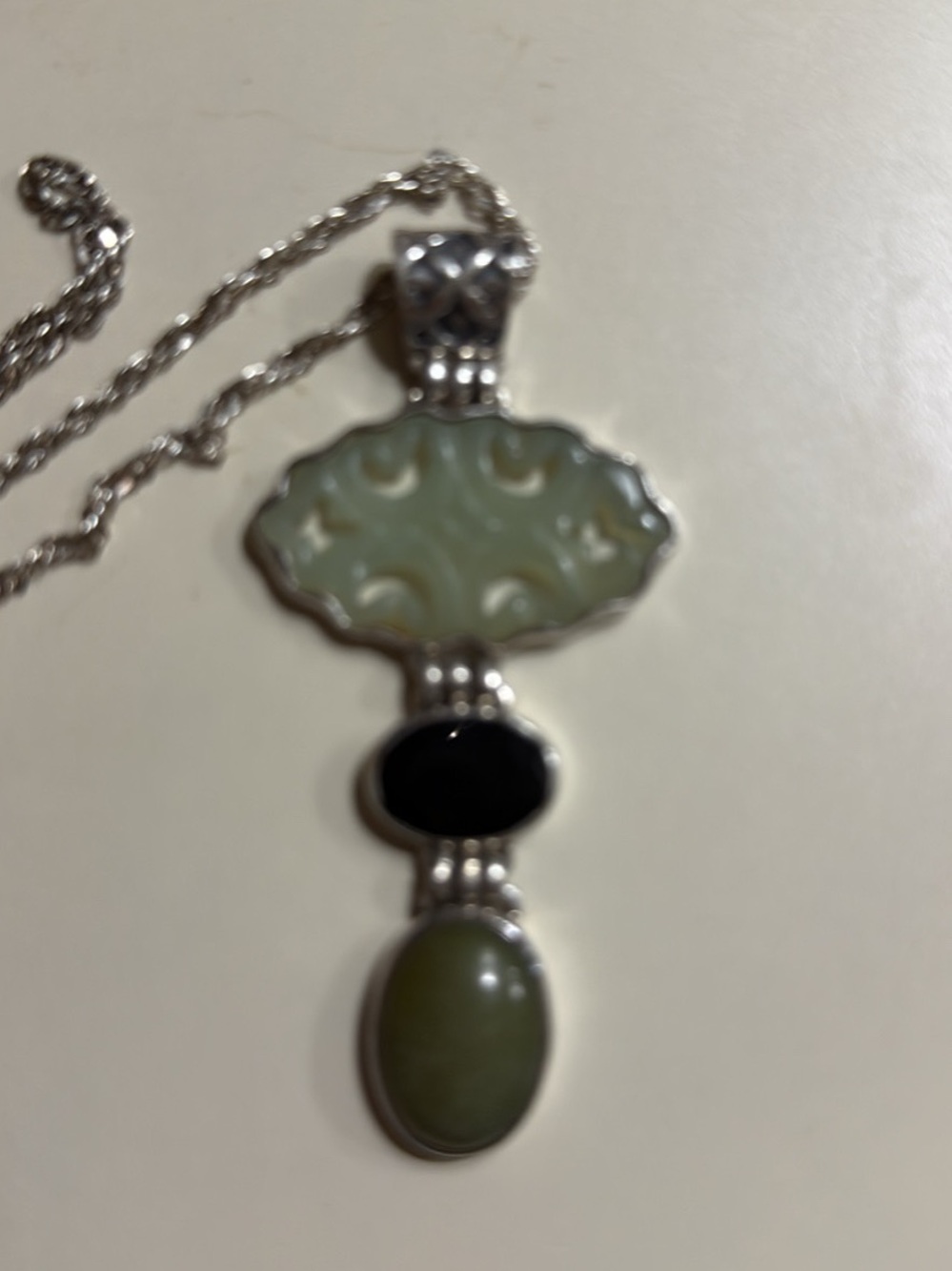 Sterling silver necklace features a carved jade pendant with black onyx